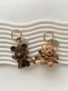 A chocolate-colored sitting bear keychain pendant, with a gold-black nose, cute and unique bag key accessory! Comes with a tag and string - resin imitation texture, sitting design, a fashionable accessory for women Keychain for Bags