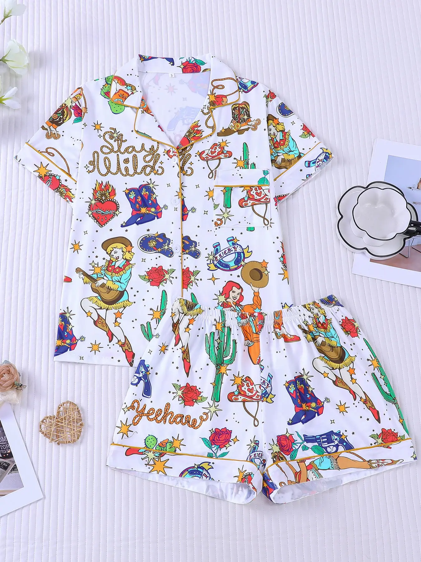 Women's 2-piece pajama set with retro Western prints including cowgirls, boots, cacti, red roses, stars, vintage guns and "Stay Wild" lettering. Gold contrast piping, lapel top with pocket, soft elastic shorts, all-season casual loungewear for women Pjs