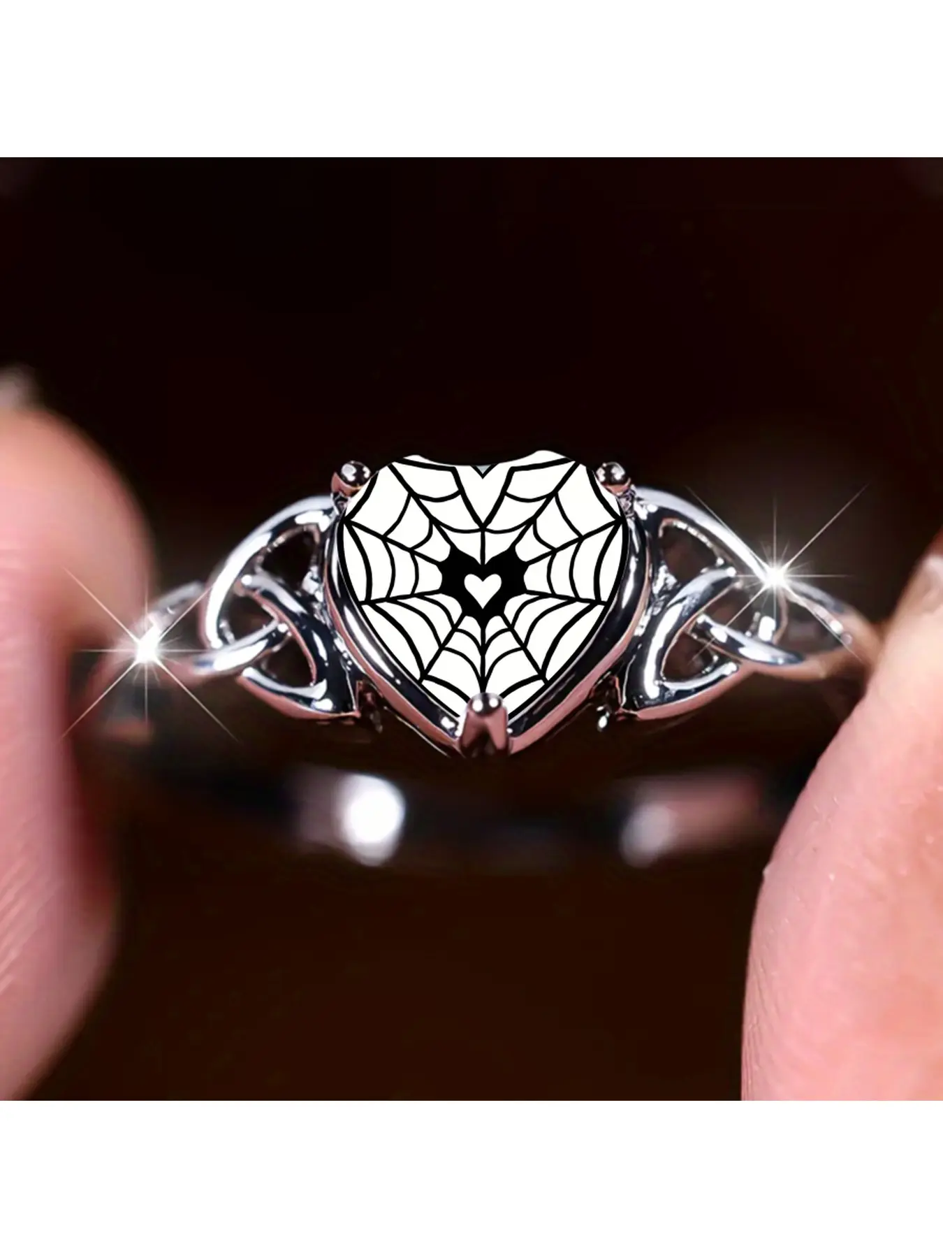 Vintage spider-web heart ring. The ring body features symmetrical Celtic knot patterns with hollow designs. The main stone is in the shape of a heart with a black spider-web pattern. There is a small heart hidden in the center of the web. This dark and sw