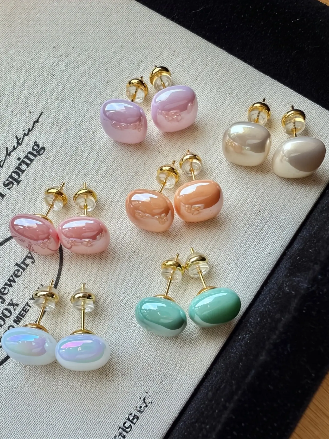 6 pairs of simple, cute, fashionable and versatile earrings Earring Stacks featuring pink beads, champagne-colored and white geometric shapes, blue-green and orange squares. High-quality jewelry