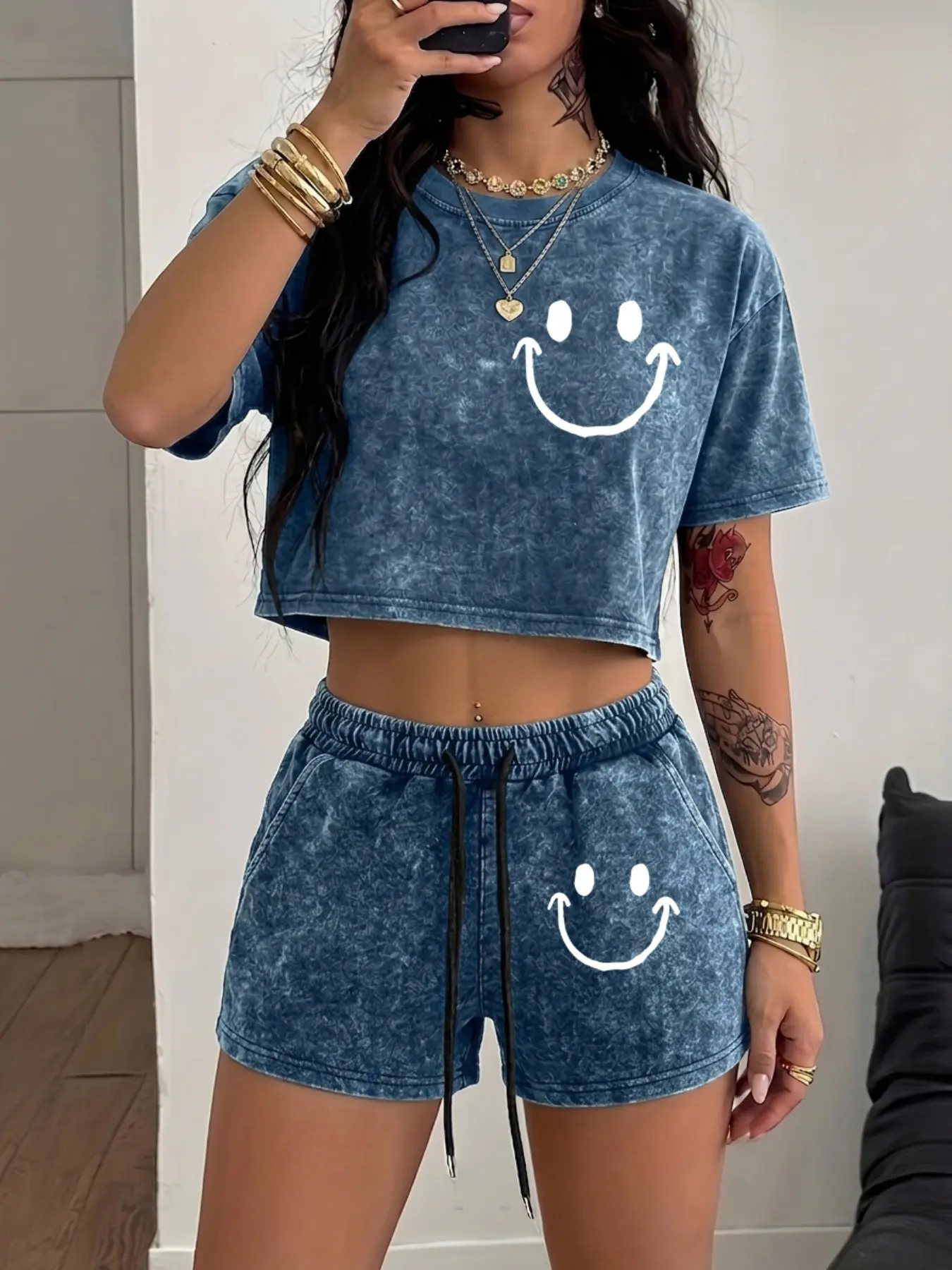 A soft, washed-cotton "It Girl" style Chic matching set featuring a cropped, midriff-baring top; both pieces share a minimalist, hand-drawn smiley face line-art print—the perfect casual effortless outfit for a laid-back look.