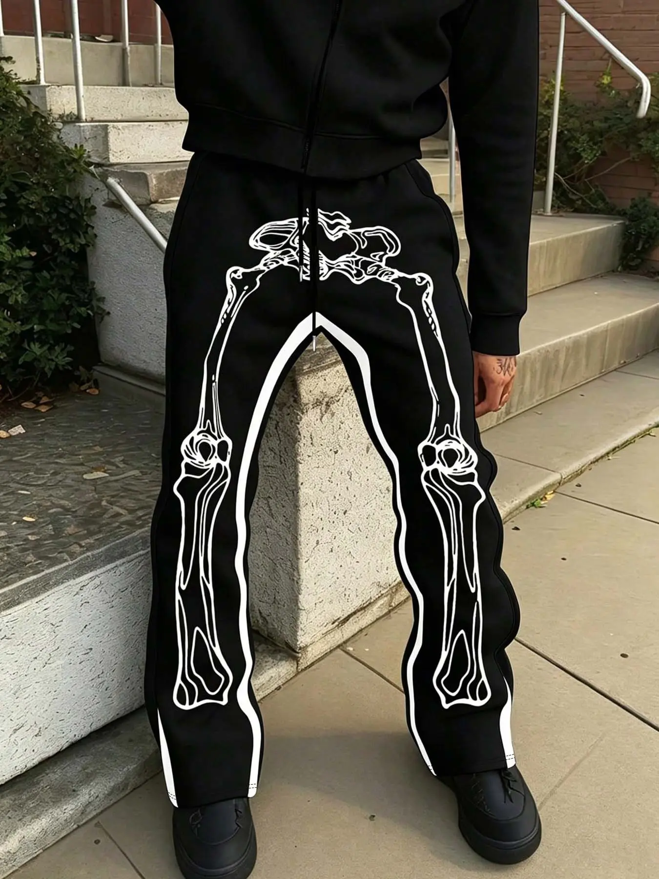 Black skull pattern printed sweatpants with white bone outline prints, drawstring wide-leg pants, gothic punk street-style casual pants, loose-fitting alternative punk hip-hop bottoms.